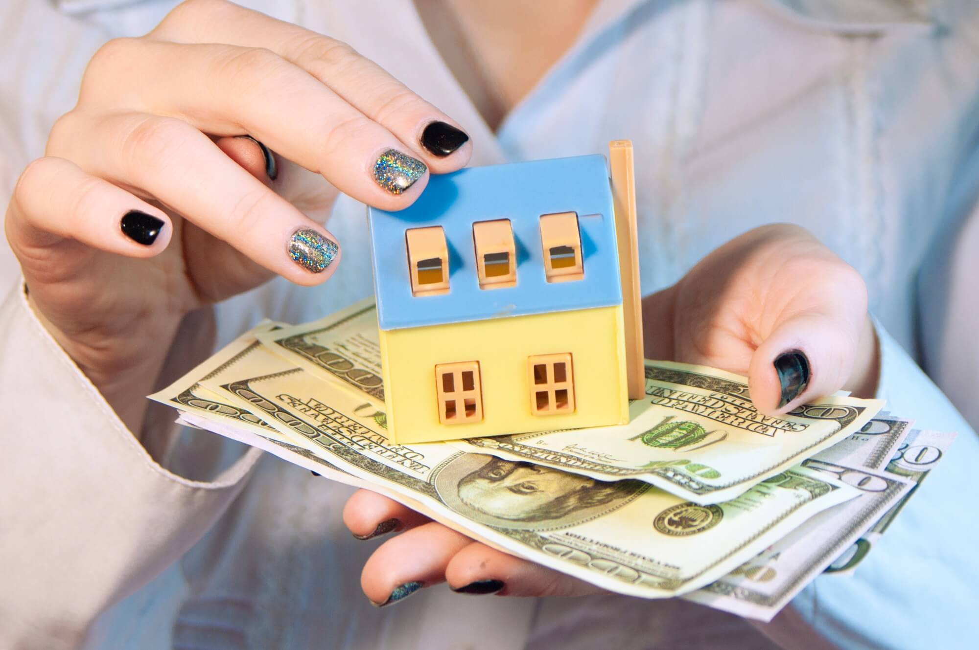girl holding a house model and money